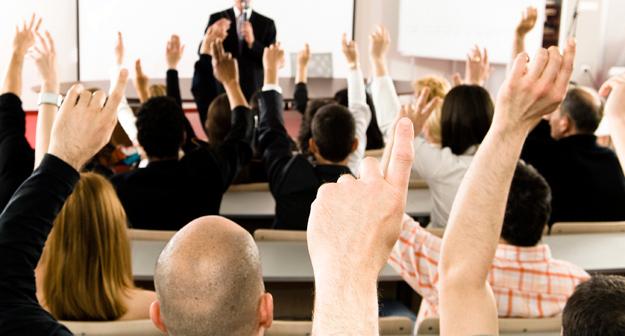 Group raising their hand in a classroom setting,